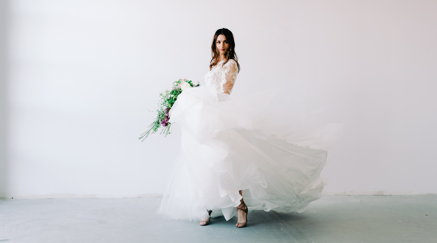 beautiful woman dancing in a wedding dress holding a bouquet of flowers
